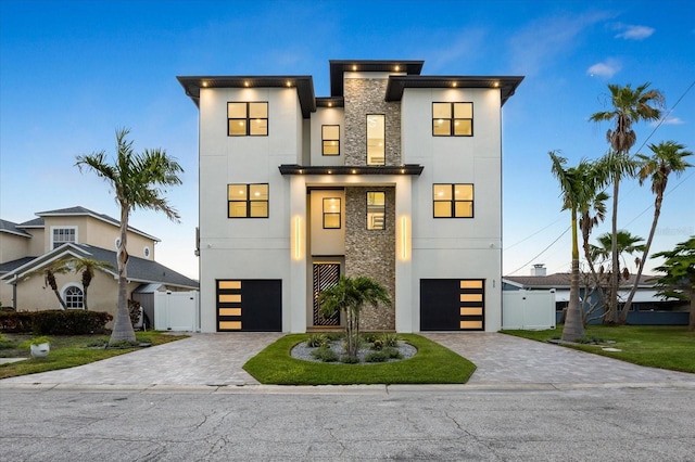 820 Bay Point Dr, Madeira Beach, FL 33708 - contemporary house featuring stucco siding, stone siding, decorative driveway, and a garage