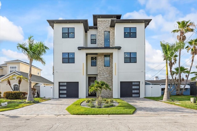 820 Bay Point Dr, Madeira Beach, FL 33708 - contemporary house with stone siding, a gate, stucco siding, and a garage