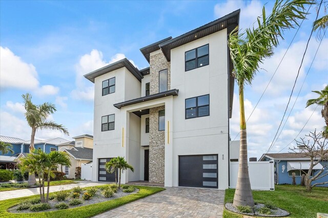 820 Bay Point Dr, Madeira Beach, FL 33708 - modern home with stucco siding, an attached garage, decorative driveway, stone siding, and a residential view