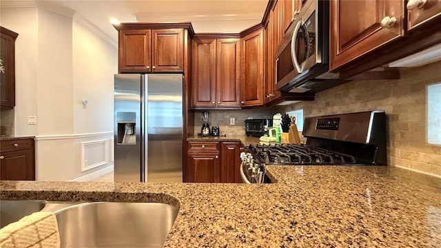 7810 Whitemarsh Way, Reunion, FL 34747 - kitchen with appliances with stainless steel finishes, light stone counters, ornamental molding, backsplash, and wainscoting