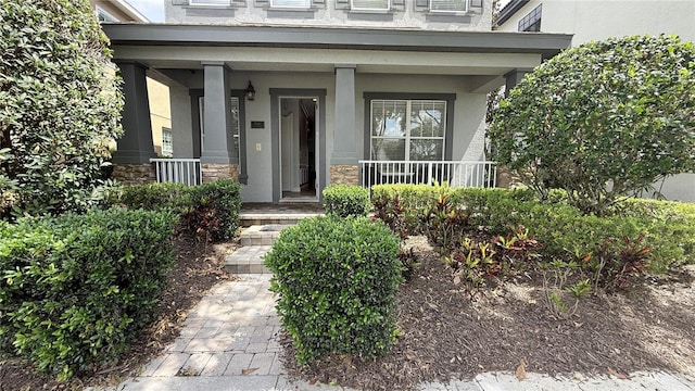 7810 Whitemarsh Way, Reunion, FL 34747 - doorway to property featuring stucco siding, covered porch, and stone siding