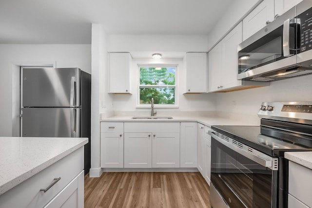 109 Magnolia Ave, Seffner, FL 33584 - kitchen featuring appliances with stainless steel finishes, light wood-style flooring, white cabinetry, and light stone counters