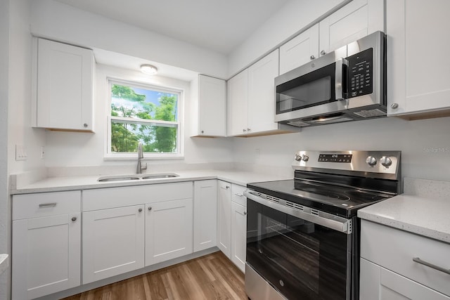 109 Magnolia Ave, Seffner, FL 33584 - kitchen with stainless steel appliances, light wood-style floors, white cabinetry, and light stone counters