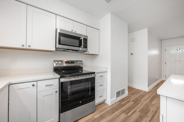 109 Magnolia Ave, Seffner, FL 33584 - kitchen with appliances with stainless steel finishes, light wood-style floors, white cabinets, and light countertops