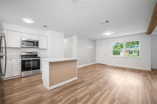 109 Magnolia Ave, Seffner, FL 33584 - kitchen with stainless steel appliances, light countertops, light wood-style floors, a kitchen island, and white cabinets