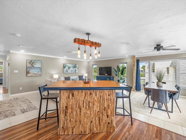 213 Fernwood Cir Unit 213, Seminole, FL 33777 - kitchen featuring a center island, plenty of natural light, crown molding, a kitchen breakfast bar, and light tile patterned floors