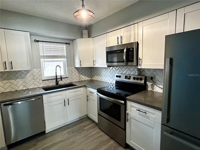 715 2nd Ave NE, Largo, FL 33770 - kitchen featuring stainless steel appliances, a sink, dark countertops, white cabinets, and a textured ceiling
