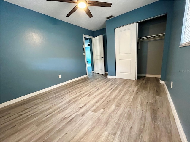 715 2nd Ave NE, Largo, FL 33770 - unfurnished bedroom featuring wood finished floors, a closet, baseboards, and a ceiling fan