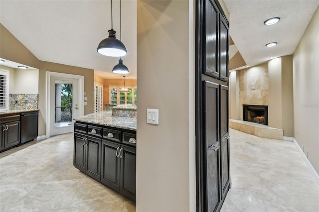 3308 Landing Pl, Palm Harbor, FL 34684 - kitchen with dishwasher, a fireplace, dark cabinetry, light stone counters, and decorative light fixtures