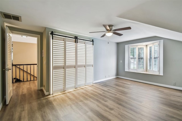 3308 Landing Pl, Palm Harbor, FL 34684 - unfurnished room with a barn door, ceiling fan, wood finished floors, and baseboards