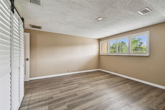 3308 Landing Pl, Palm Harbor, FL 34684 - empty room featuring a barn door, a textured ceiling, baseboards, and wood finished floors