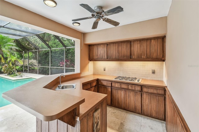 3308 Landing Pl, Palm Harbor, FL 34684 - kitchen with a sink, a sunroom, a peninsula, stainless steel gas stovetop, and tasteful backsplash