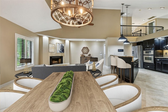 3308 Landing Pl, Palm Harbor, FL 34684 - dining area with a high ceiling, a lit fireplace, a chandelier, and baseboards