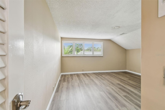 3308 Landing Pl, Palm Harbor, FL 34684 - bonus room with a textured ceiling, wood finished floors, vaulted ceiling, and baseboards