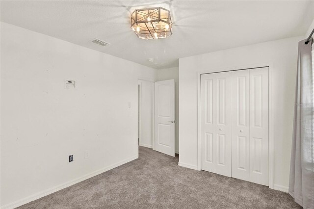 271 Inman Blvd, Winter Haven, FL 33881 - unfurnished bedroom with carpet flooring, a closet, baseboards, and a chandelier