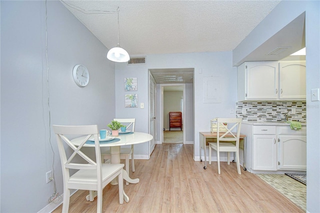 4801 Airport Rd Unit 211, Zephyrhills, FL 33542 - dining area with light wood-type flooring, a textured ceiling, and baseboards