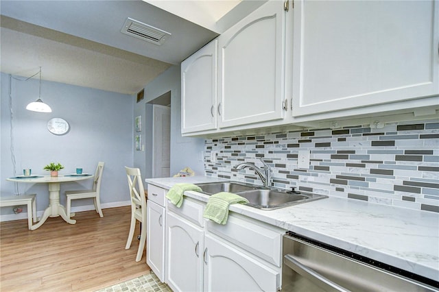 4801 Airport Rd Unit 211, Zephyrhills, FL 33542 - kitchen featuring stainless steel dishwasher, white cabinetry, decorative backsplash, baseboards, and hanging light fixtures