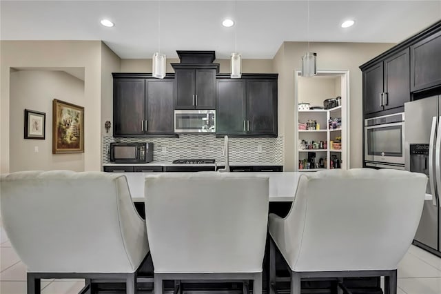 4155 Barletta Ct, Wesley Chapel, FL 33543 - kitchen with stainless steel appliances, light countertops, decorative backsplash, hanging light fixtures, and recessed lighting