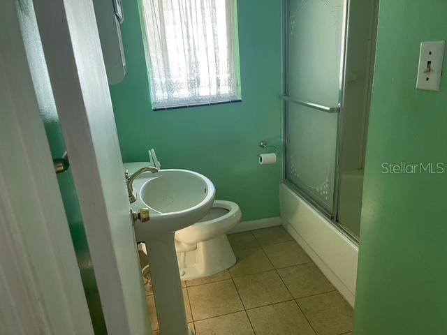 15034 Lake Magdalene Blvd, Tampa, FL 33618 - full bathroom with tile patterned floors, toilet, and bath / shower combo with glass door
