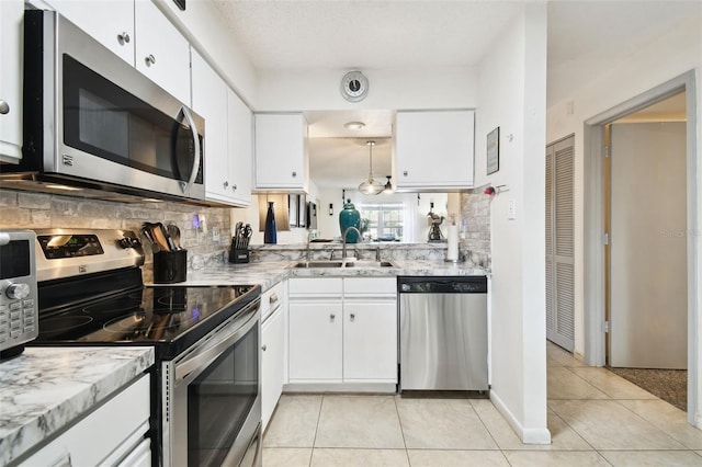 6630 Spring Flower Dr Unit 14, New Port Richey, FL 34653 - kitchen featuring appliances with stainless steel finishes, a sink, light tile patterned flooring, tasteful backsplash, and white cabinets