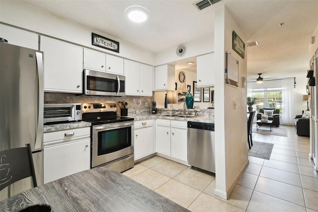 6630 Spring Flower Dr Unit 14, New Port Richey, FL 34653 - kitchen featuring stainless steel appliances, a sink, backsplash, white cabinets, and light tile patterned floors
