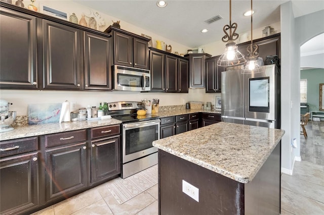 12316 Streambed Dr, Riverview, FL 33579 - kitchen featuring stainless steel appliances, arched walkways, light stone counters, dark brown cabinets, and pendant lighting