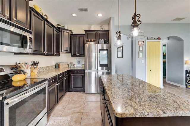 12316 Streambed Dr, Riverview, FL 33579 - kitchen with appliances with stainless steel finishes, arched walkways, a kitchen island, light stone countertops, and recessed lighting