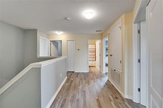 12316 Streambed Dr, Riverview, FL 33579 - hallway featuring wood finished floors, an upstairs landing, a textured ceiling, and baseboards