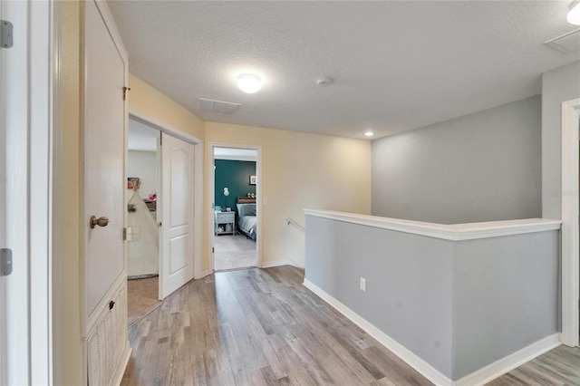 12316 Streambed Dr, Riverview, FL 33579 - hallway featuring an upstairs landing, light wood finished floors, a textured ceiling, and baseboards