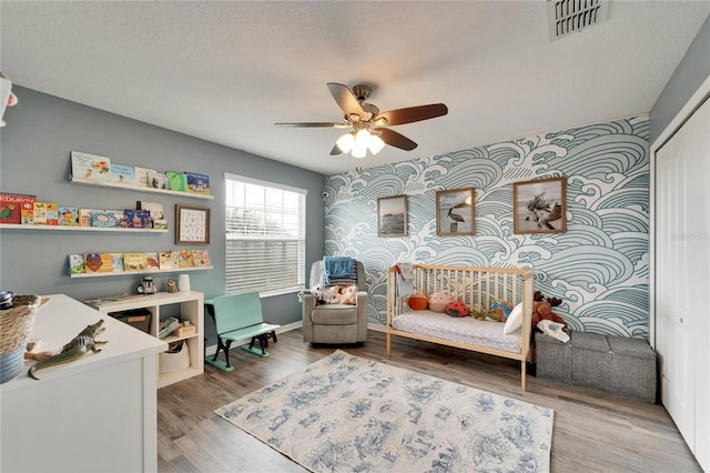 12316 Streambed Dr, Riverview, FL 33579 - bedroom with an accent wall, wallpapered walls, light wood-type flooring, and ceiling fan