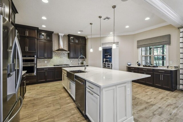 9080 Morgana Ct, Winter Garden, FL 34787 - kitchen with appliances with stainless steel finishes, wall chimney range hood, a sink, light wood-style flooring, and tasteful backsplash
