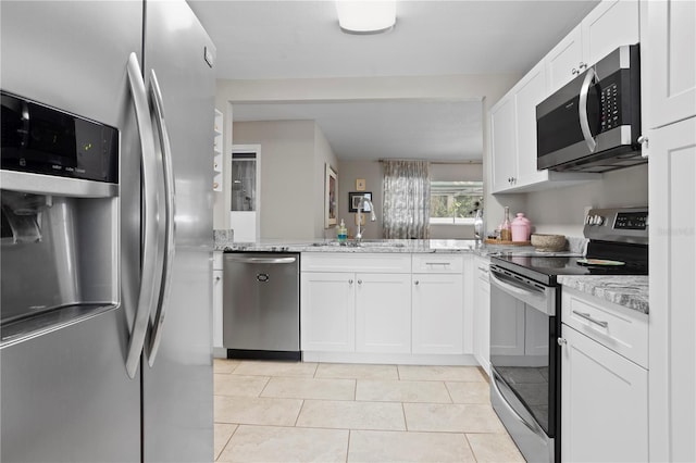 4012 N Munro St, Tampa, FL 33603 - kitchen featuring stainless steel appliances, white cabinets, light stone counters, light tile patterned flooring, and a peninsula