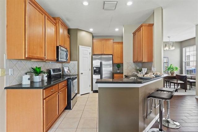 589 52nd Ave N, Saint Petersburg, FL 33703 - kitchen featuring stainless steel appliances, dark countertops, a breakfast bar area, a peninsula, and brown cabinetry