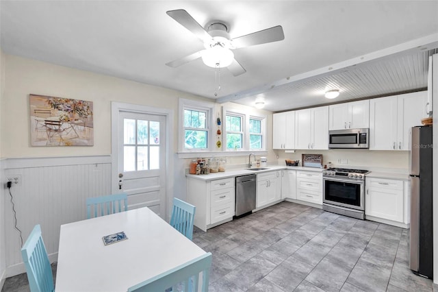 320 Broadway, Dunedin, FL 34698 - kitchen featuring appliances with stainless steel finishes, a sink, a wainscoted wall, light countertops, and white cabinets