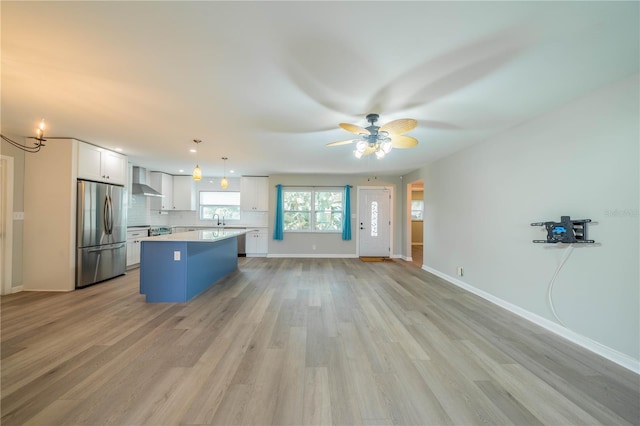 117 Connie Ave, Tampa, FL 33613 - kitchen featuring freestanding refrigerator, wall chimney exhaust hood, a center island, white cabinetry, and light countertops
