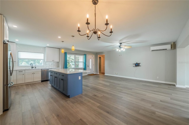 117 Connie Ave, Tampa, FL 33613 - kitchen featuring appliances with stainless steel finishes, an AC wall unit, ceiling fan, light wood-style floors, and a chandelier