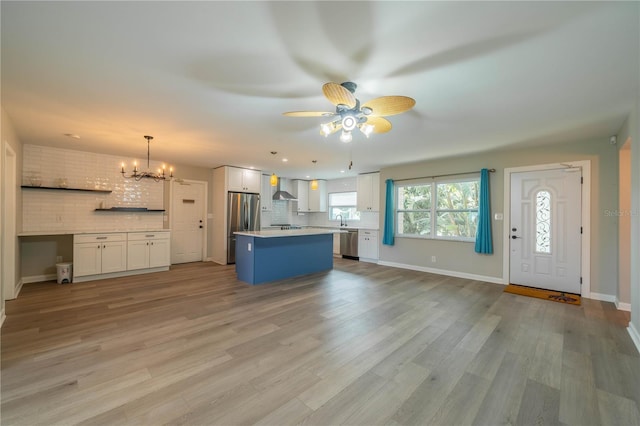 117 Connie Ave, Tampa, FL 33613 - kitchen featuring appliances with stainless steel finishes, wall chimney exhaust hood, white cabinetry, tasteful backsplash, and light countertops