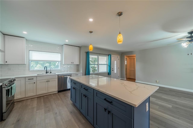 117 Connie Ave, Tampa, FL 33613 - kitchen with stainless steel appliances, light wood finished floors, a sink, tasteful backsplash, and white cabinetry