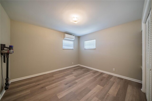 117 Connie Ave, Tampa, FL 33613 - unfurnished bedroom featuring a wall unit AC, wood finished floors, and baseboards