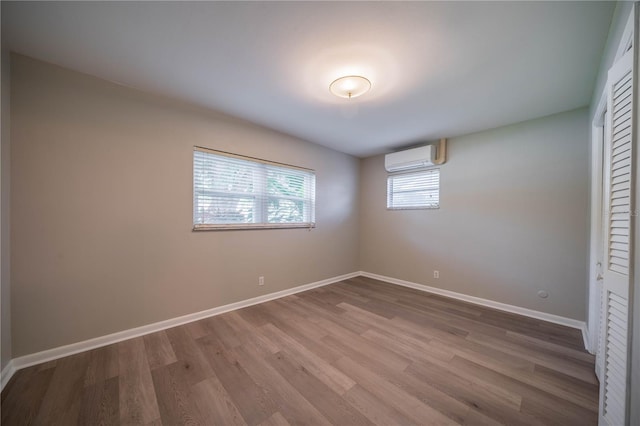 117 Connie Ave, Tampa, FL 33613 - unfurnished bedroom featuring an AC wall unit, wood finished floors, baseboards, and a closet