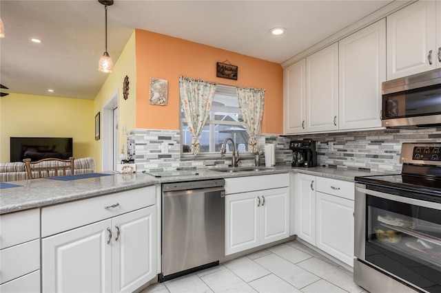 460 Meravan Dr, Palm Harbor, FL 34683 - kitchen featuring appliances with stainless steel finishes, a sink, tasteful backsplash, pendant lighting, and white cabinets