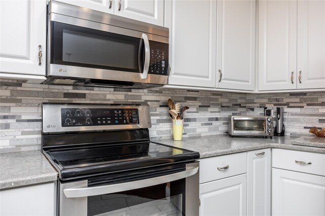 460 Meravan Dr, Palm Harbor, FL 34683 - kitchen featuring stainless steel appliances, tasteful backsplash, and white cabinetry