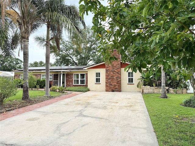 2523 Krueger Ln, Tampa, FL 33618 - view of front of property with stucco siding, driveway, a front yard, solar panels, and a chimney