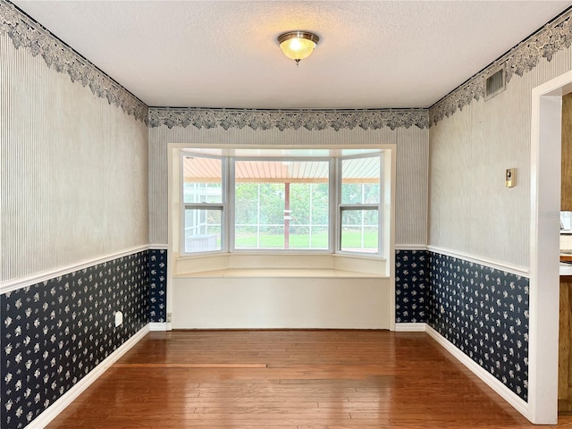 2523 Krueger Ln, Tampa, FL 33618 - empty room with wallpapered walls, hardwood / wood-style floors, a textured ceiling, and baseboards