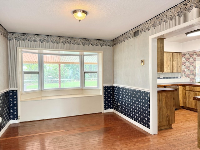 2523 Krueger Ln, Tampa, FL 33618 - unfurnished dining area with wallpapered walls, light wood-style floors, healthy amount of natural light, baseboards, and a textured ceiling