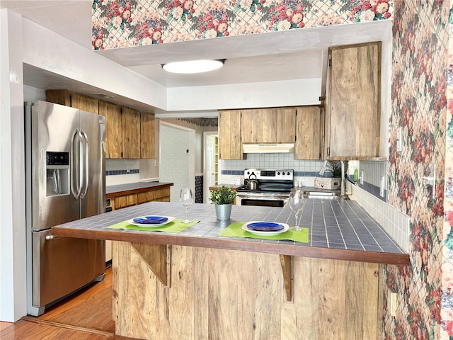 2523 Krueger Ln, Tampa, FL 33618 - kitchen with appliances with stainless steel finishes, under cabinet range hood, tile countertops, tasteful backsplash, and a peninsula