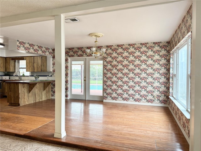 2523 Krueger Ln, Tampa, FL 33618 - unfurnished dining area with wallpapered walls, light wood-type flooring, baseboards, and a sink