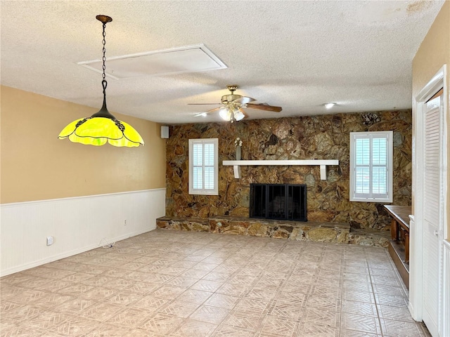 2523 Krueger Ln, Tampa, FL 33618 - unfurnished living room featuring a textured ceiling, ceiling fan, a wainscoted wall, a fireplace, and attic access