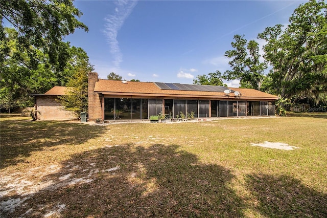 309 Hidden Lake Dr, Brandon, FL 33511 - rear view of house featuring a sunroom, solar panels, a chimney, and a lawn
