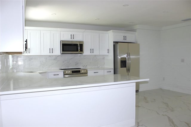 1109 N Obrien St, Tampa, FL 33607 - kitchen with appliances with stainless steel finishes, a peninsula, white cabinets, light marble finish flooring, and backsplash